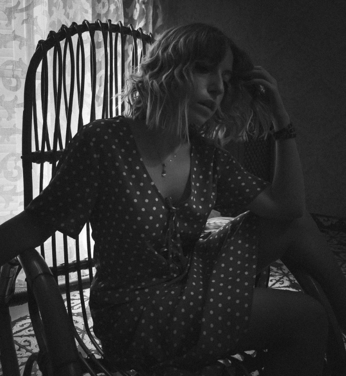 a woman in a polka dot dress sitting on a chair